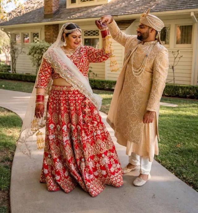 plus size bridal couple celebrating outdoors in traditional red and gold wedding attire.